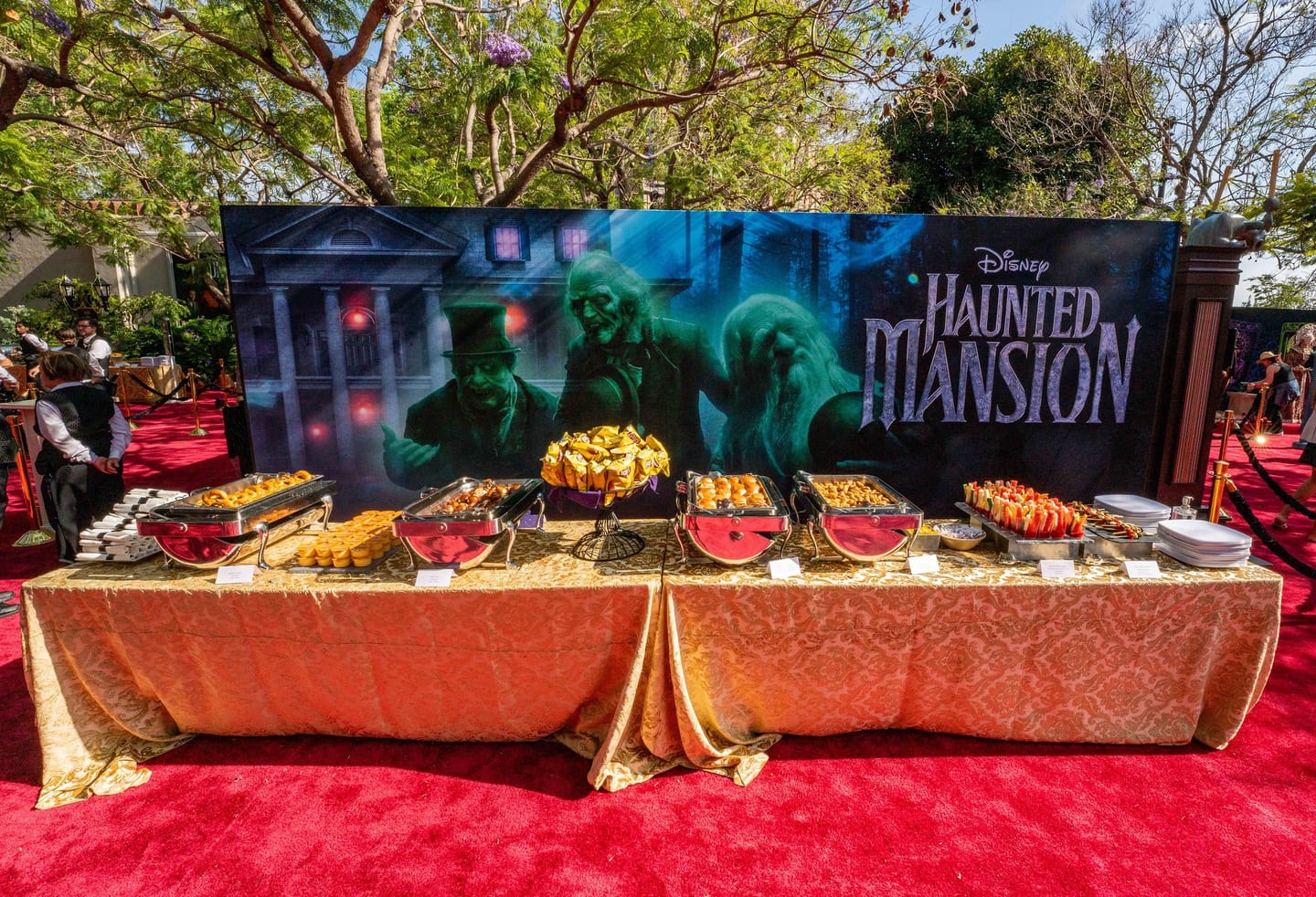 Themed food display in front of a Disney Haunted Mansion backdrop with the three hitchhiking ghosts at the film’s Los Angeles premiere
