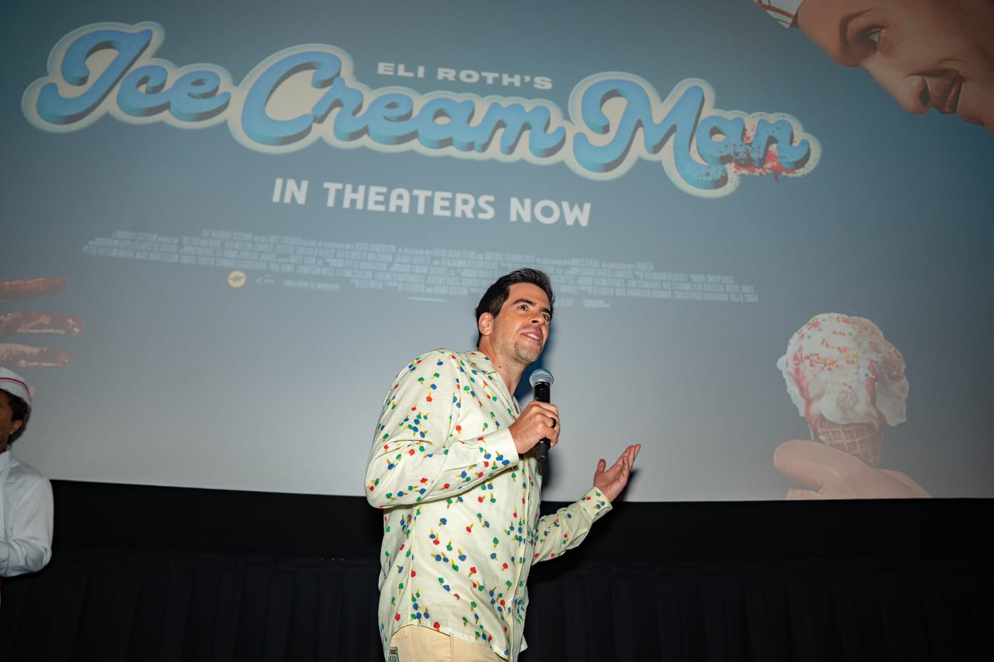 Eli Roth speaking into a microphone in front of the cinema screen showing the Eli Roth’s Ice Cream Man title card at AMC The Americana at Brand