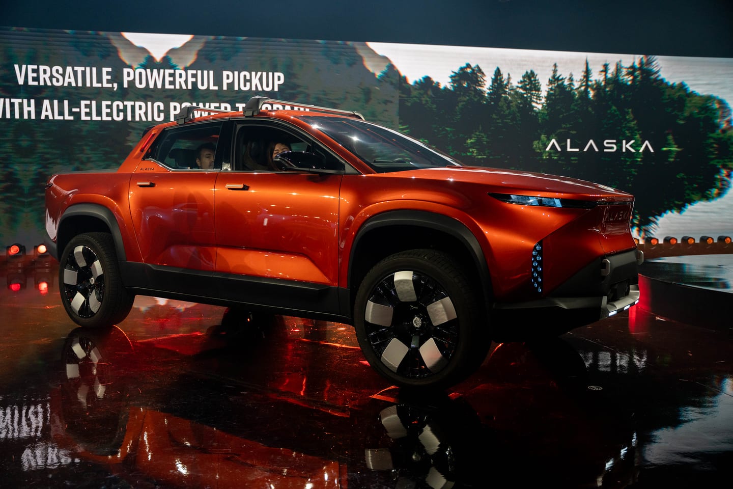 The orange Fisker Alaska on the reveal stage beneath the Alaska screen