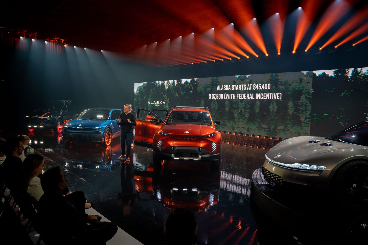 The vehicle lineup on stage with Alaska pricing on the screen