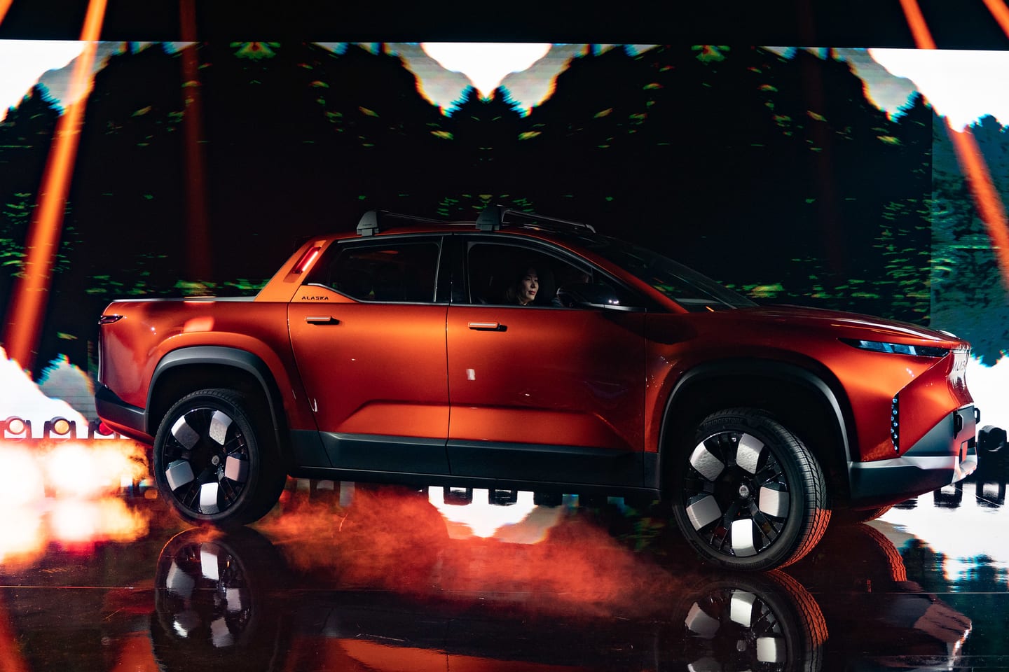 Side profile of the orange Fisker Alaska pickup on the reveal stage