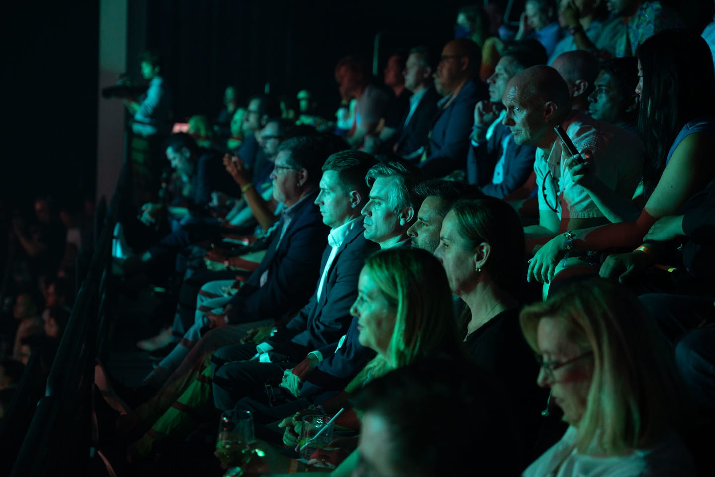The seated audience in teal stage light at the Fisker reveal