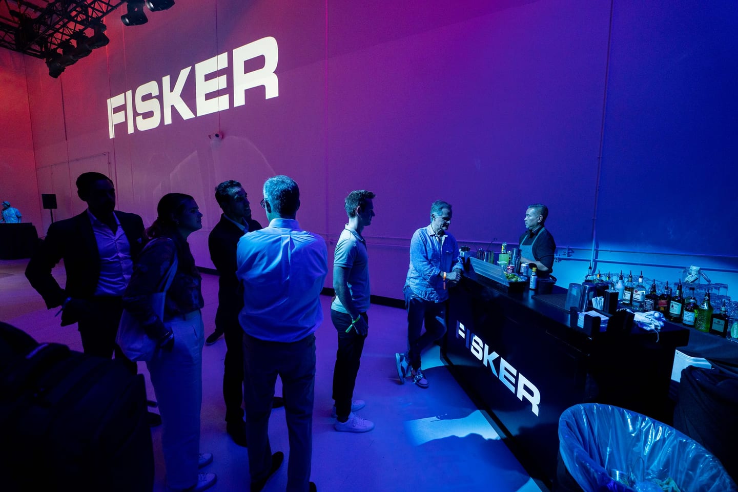 Guests at the bar beneath an illuminated FISKER wall