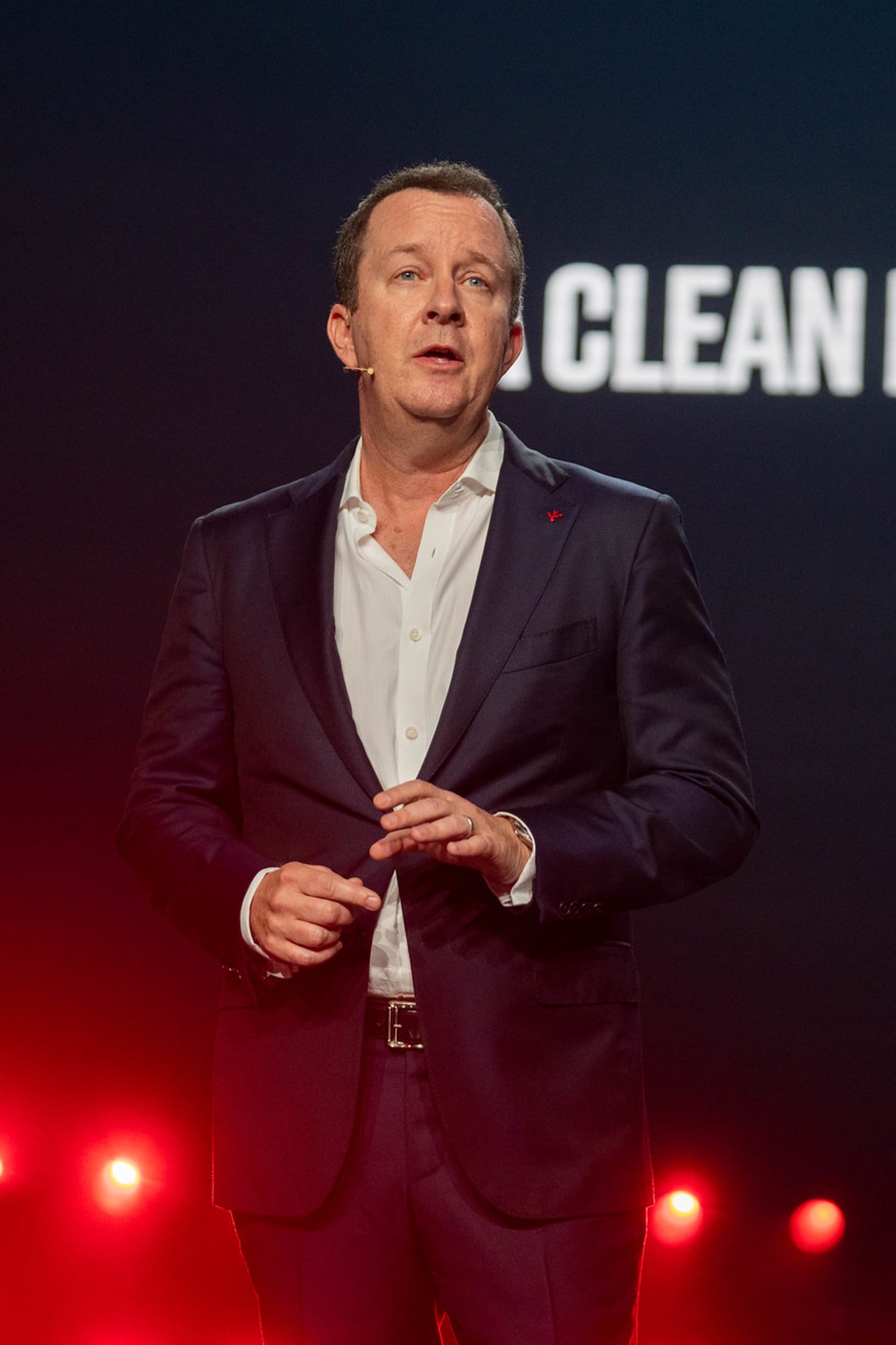 A speaker on stage in front of a screen reading Clean Future For All