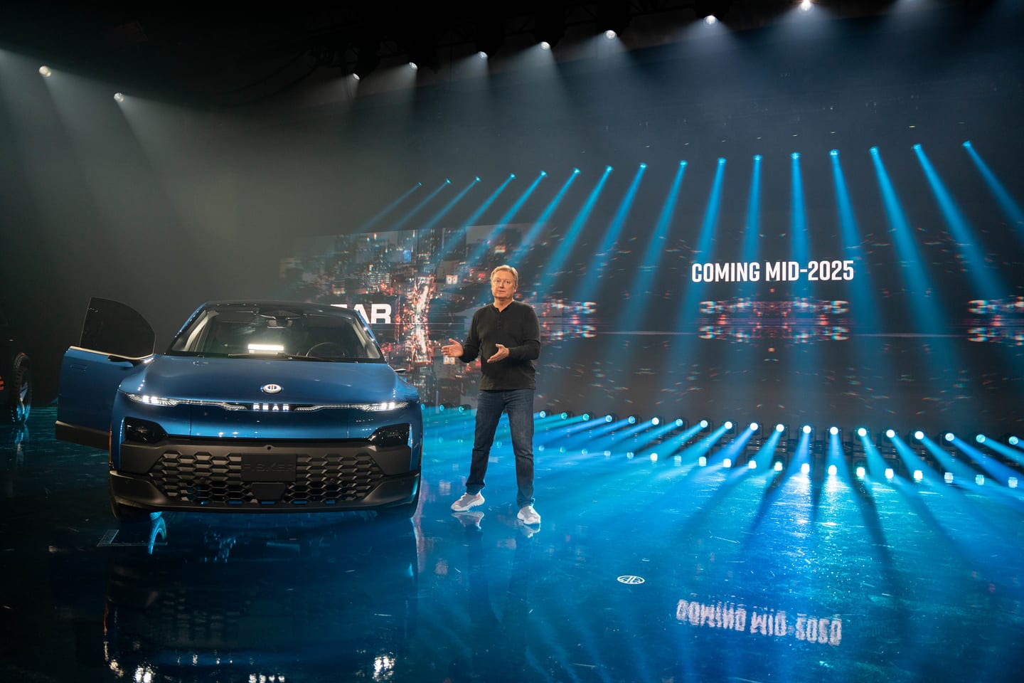 A presenter beside a Fisker vehicle, the screen reading Coming mid-2025