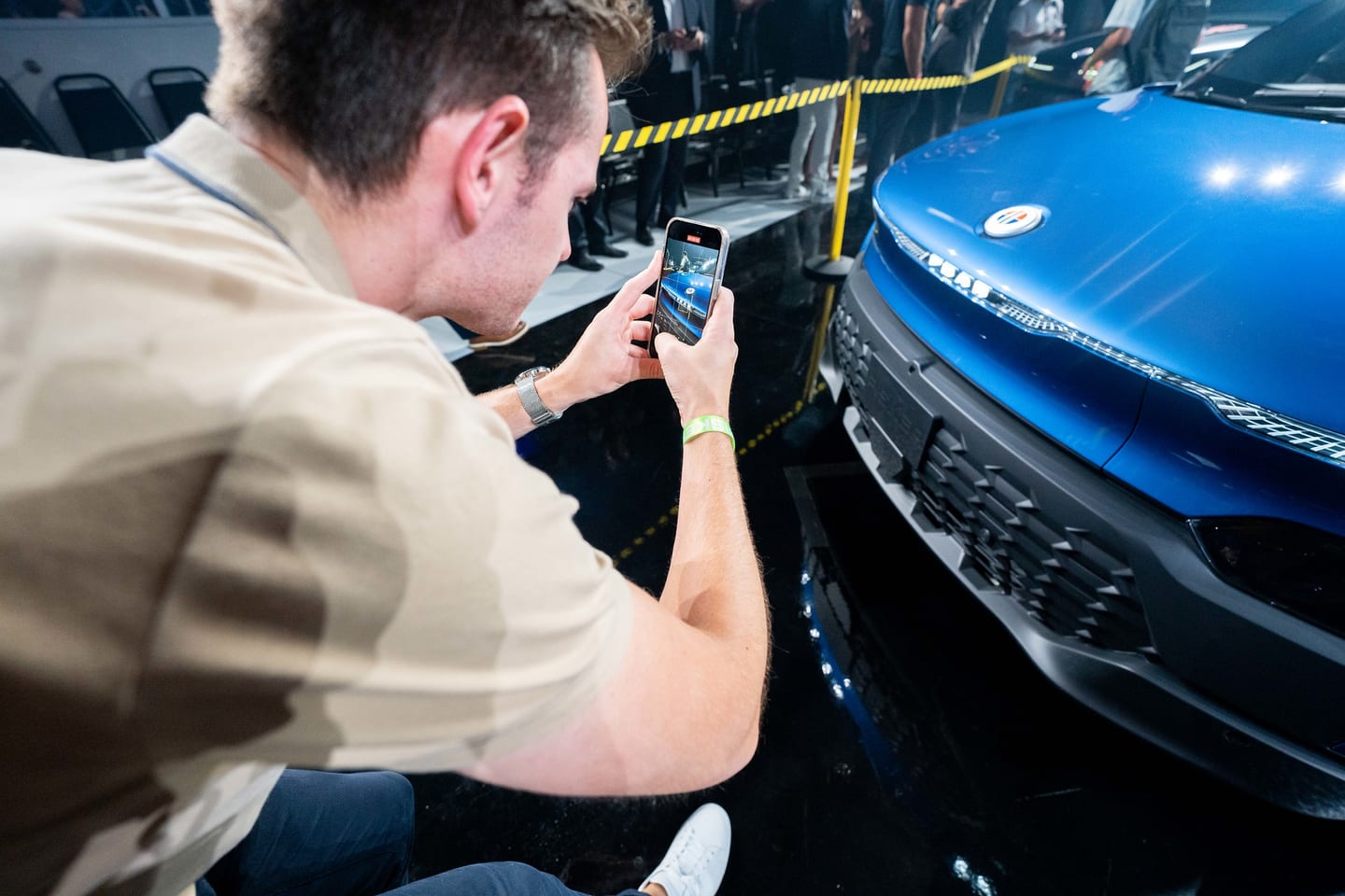 A guest photographing a blue Fisker vehicle on his phone