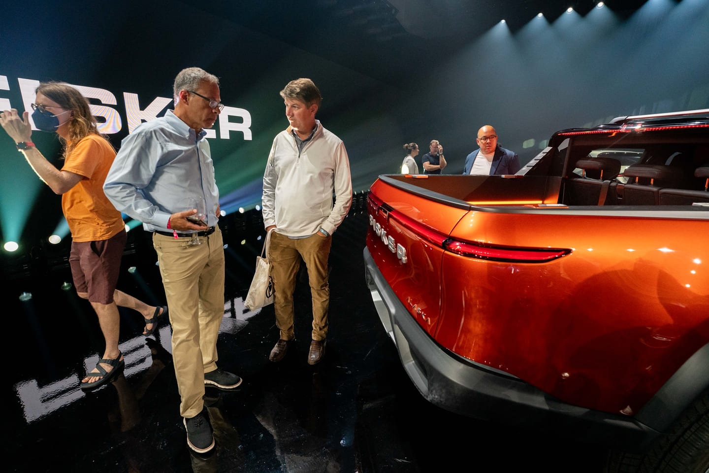 Guests inspecting the rear of the orange Fisker Alaska