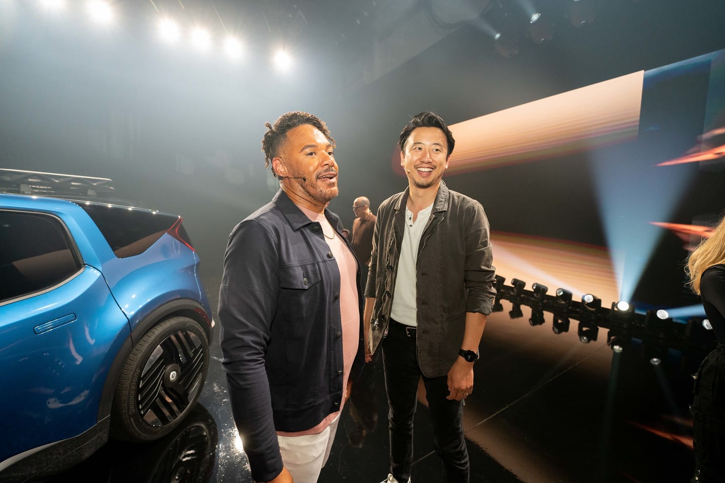 Two guests photographed beside a blue Fisker vehicle