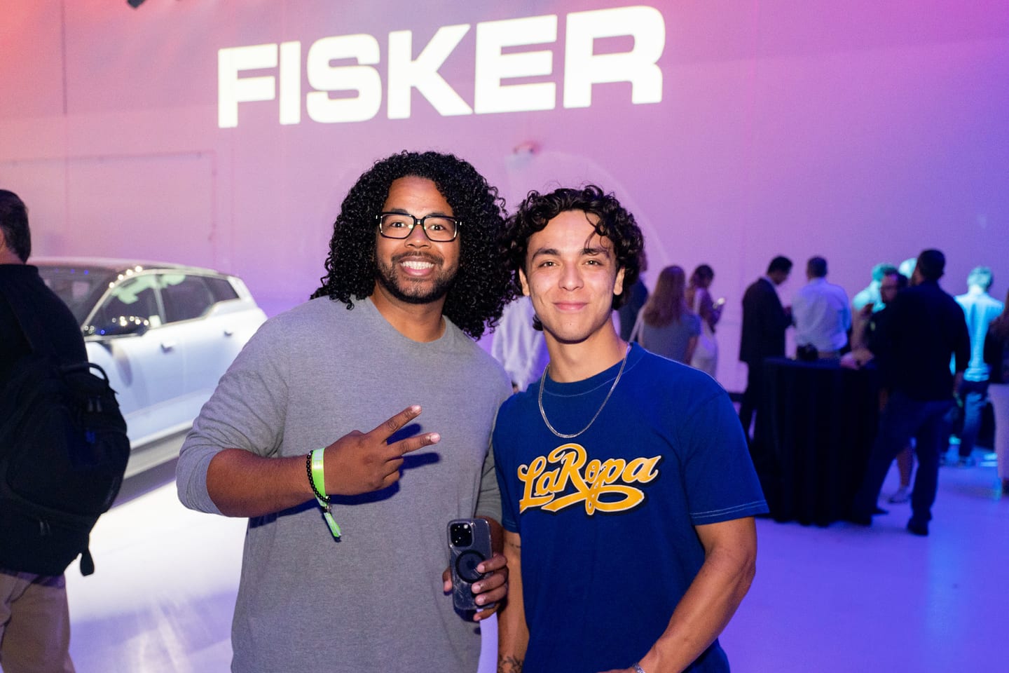 Two guests photographed together in front of a FISKER screen