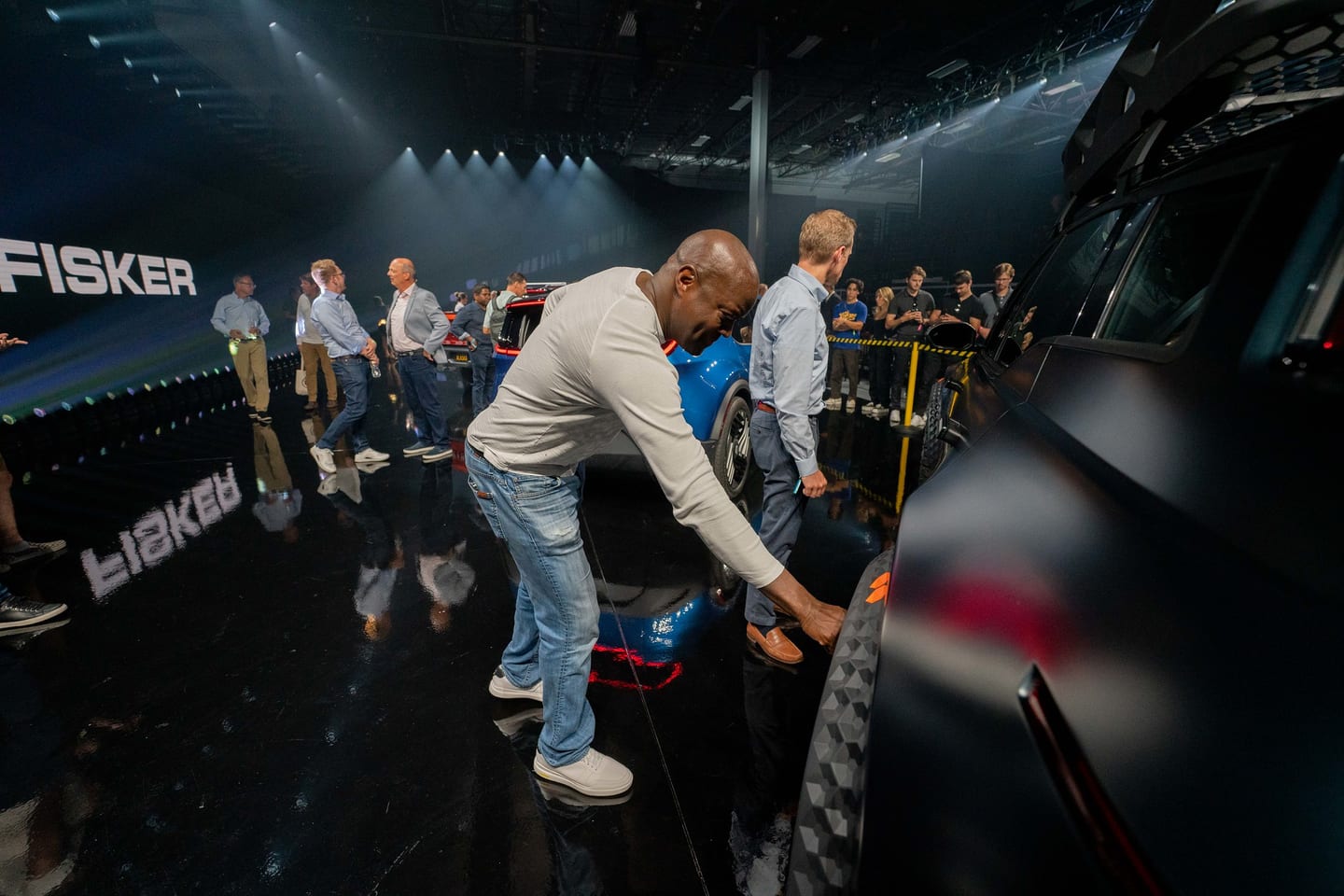 Guests leaning over a rope to look at a Fisker vehicle