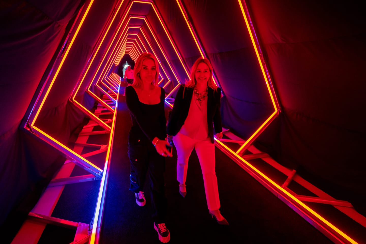 Two guests walking through a red and blue neon tunnel activation