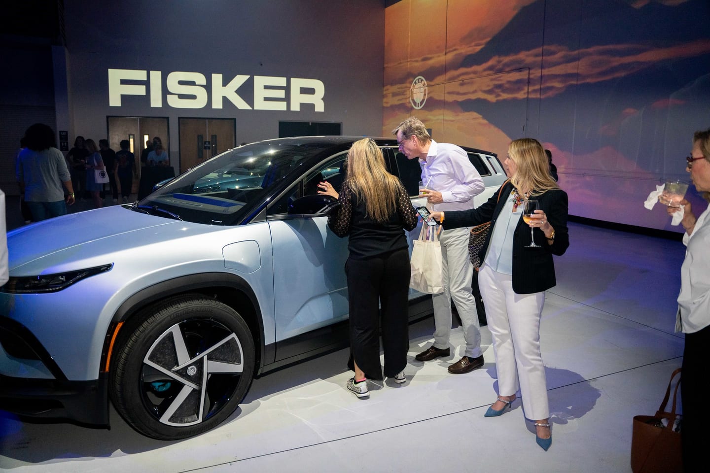 Guests around a white Fisker Ocean beneath a FISKER backdrop