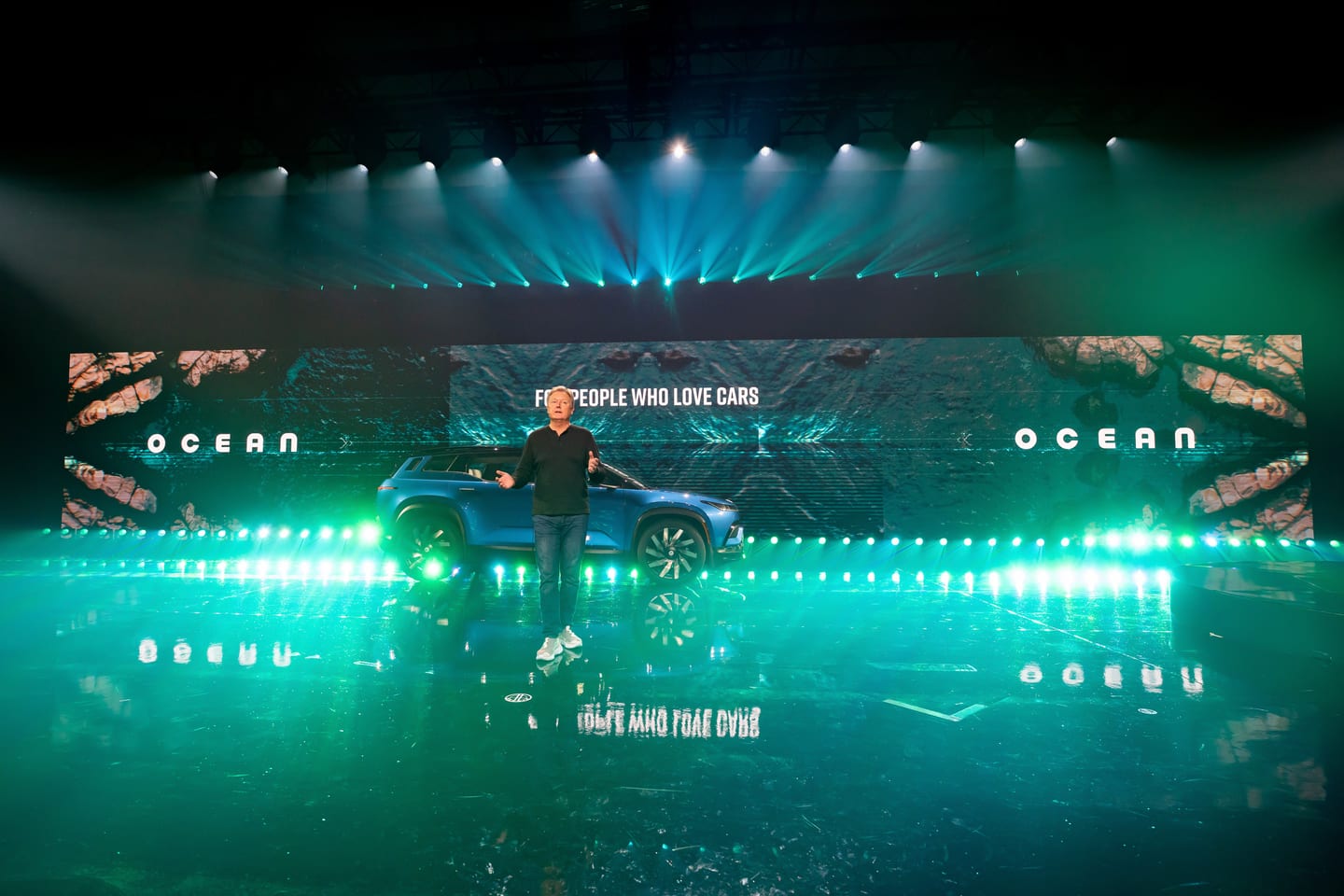 A presenter on the green-lit stage with OCEAN across the screen