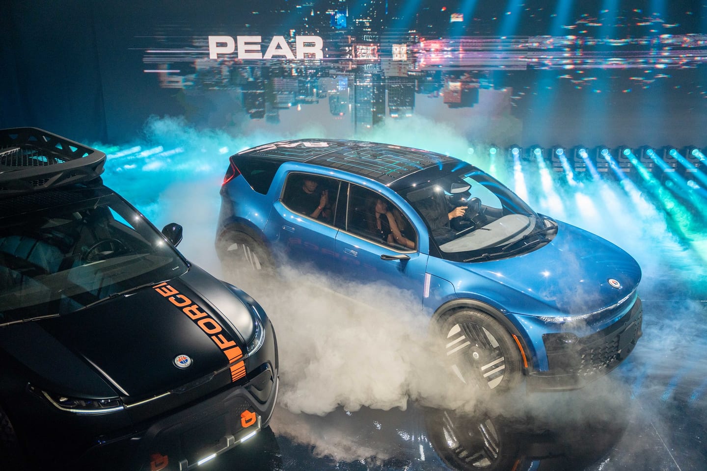 The Fisker PEAR on stage in smoke beside a second vehicle
