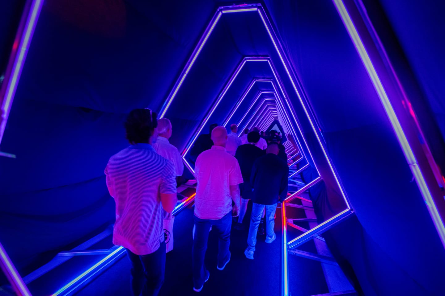 Guests silhouetted inside the blue neon tunnel activation