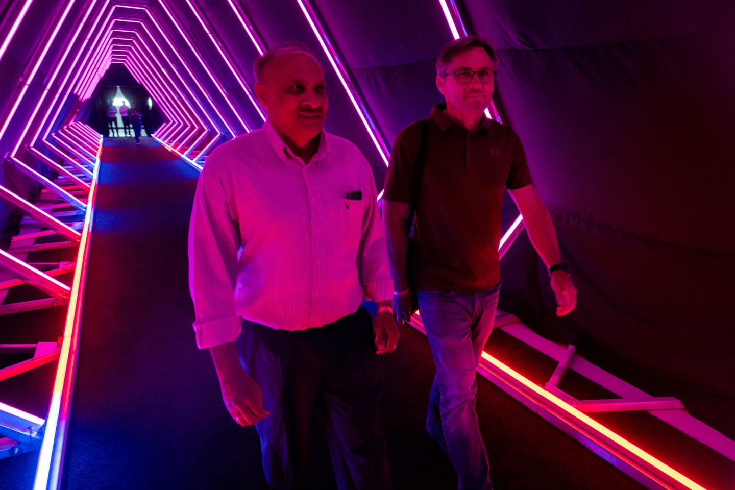 Two guests inside the pink and blue neon tunnel