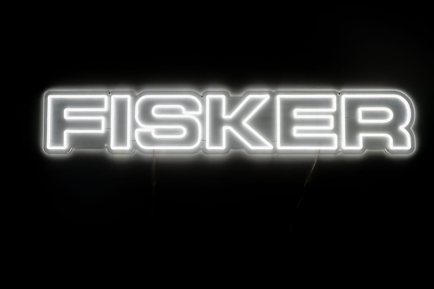 The illuminated FISKER wordmark on a dark wall