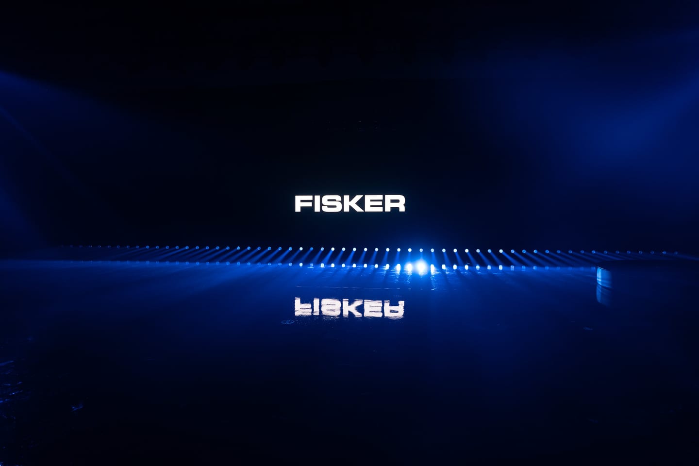 The FISKER wordmark reflected on the wet stage floor