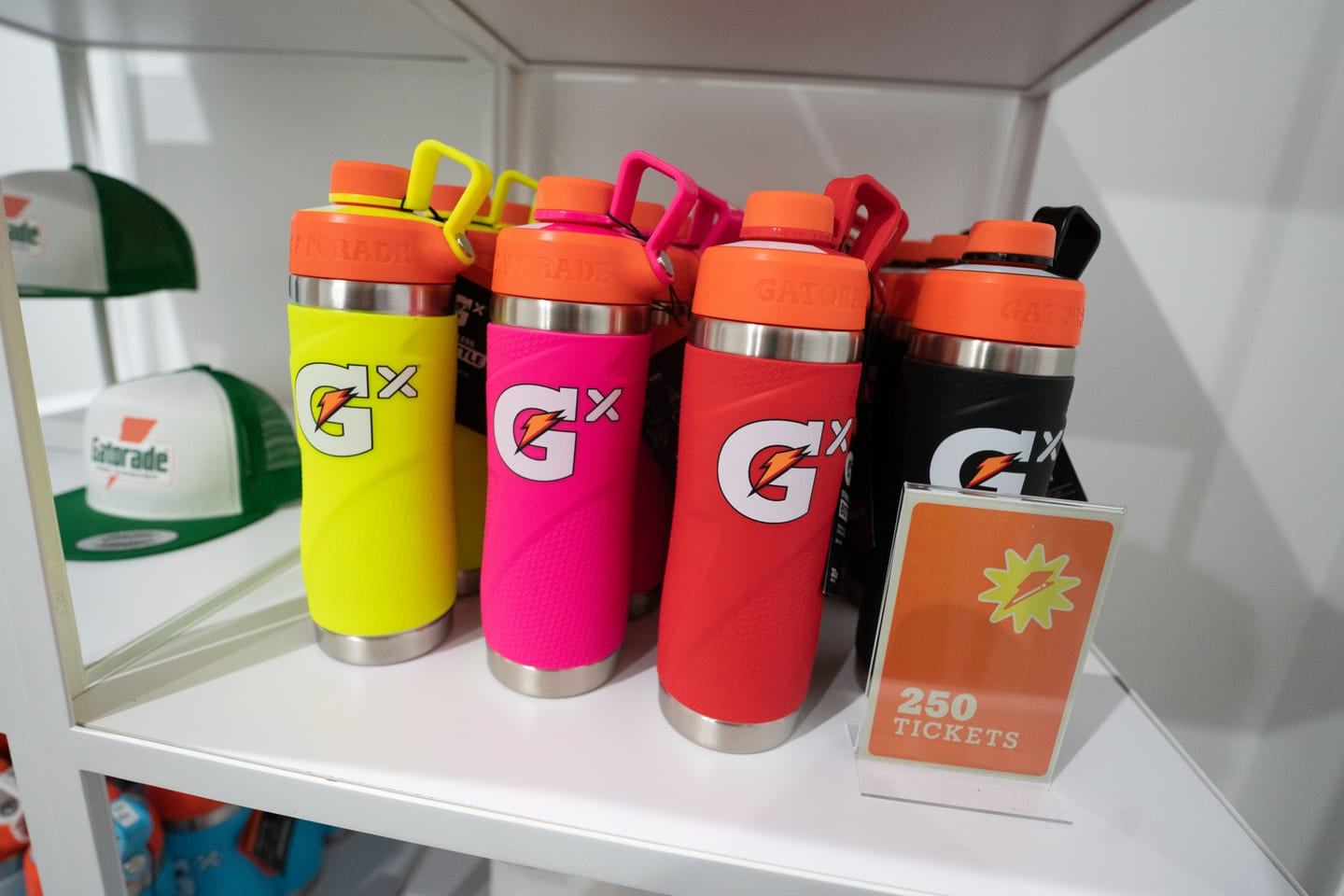 Branded Gatorade Gx bottles in pink, yellow and orange lined up on a gifting table