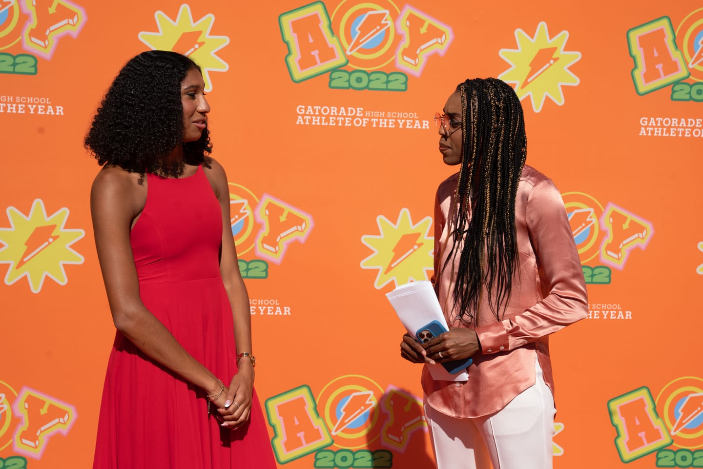 Two honorees photographed together in front of the orange Athlete of the Year step-and-repeat