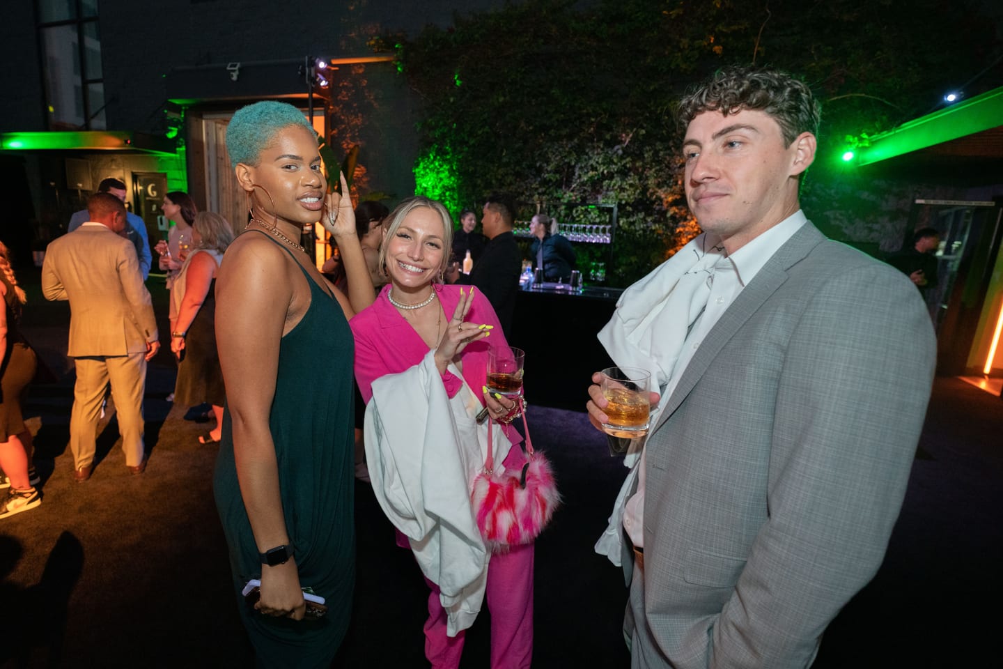 A group of guests photographed together at the after-party in green light