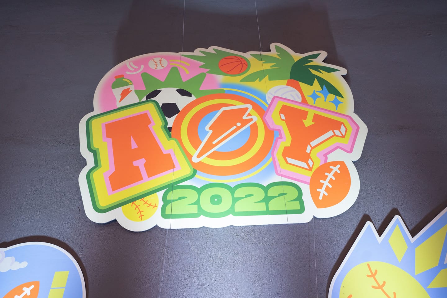 The AOY 2022 logo — a sunburst holding a football, soccer ball and basketball — projected on the venue floor