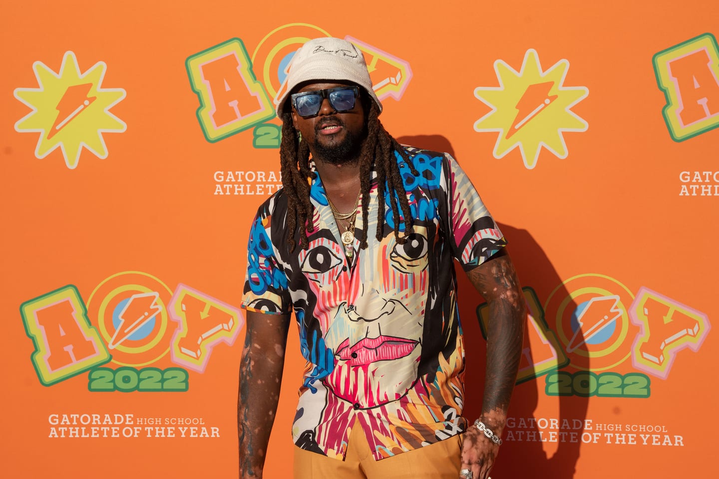 A guest in a bucket hat and patterned shirt on the AOY 2022 step-and-repeat