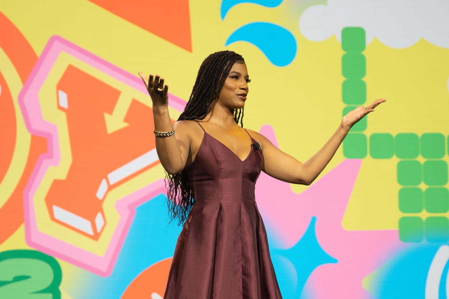 A host presenting on stage in front of bright illustrated AOY graphics