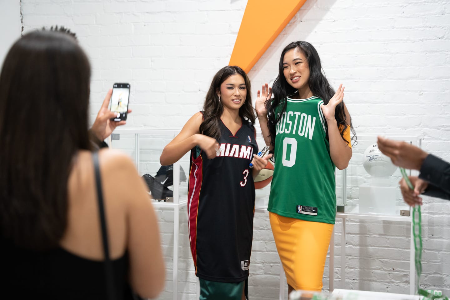 Two guests in basketball jerseys being filmed on a phone