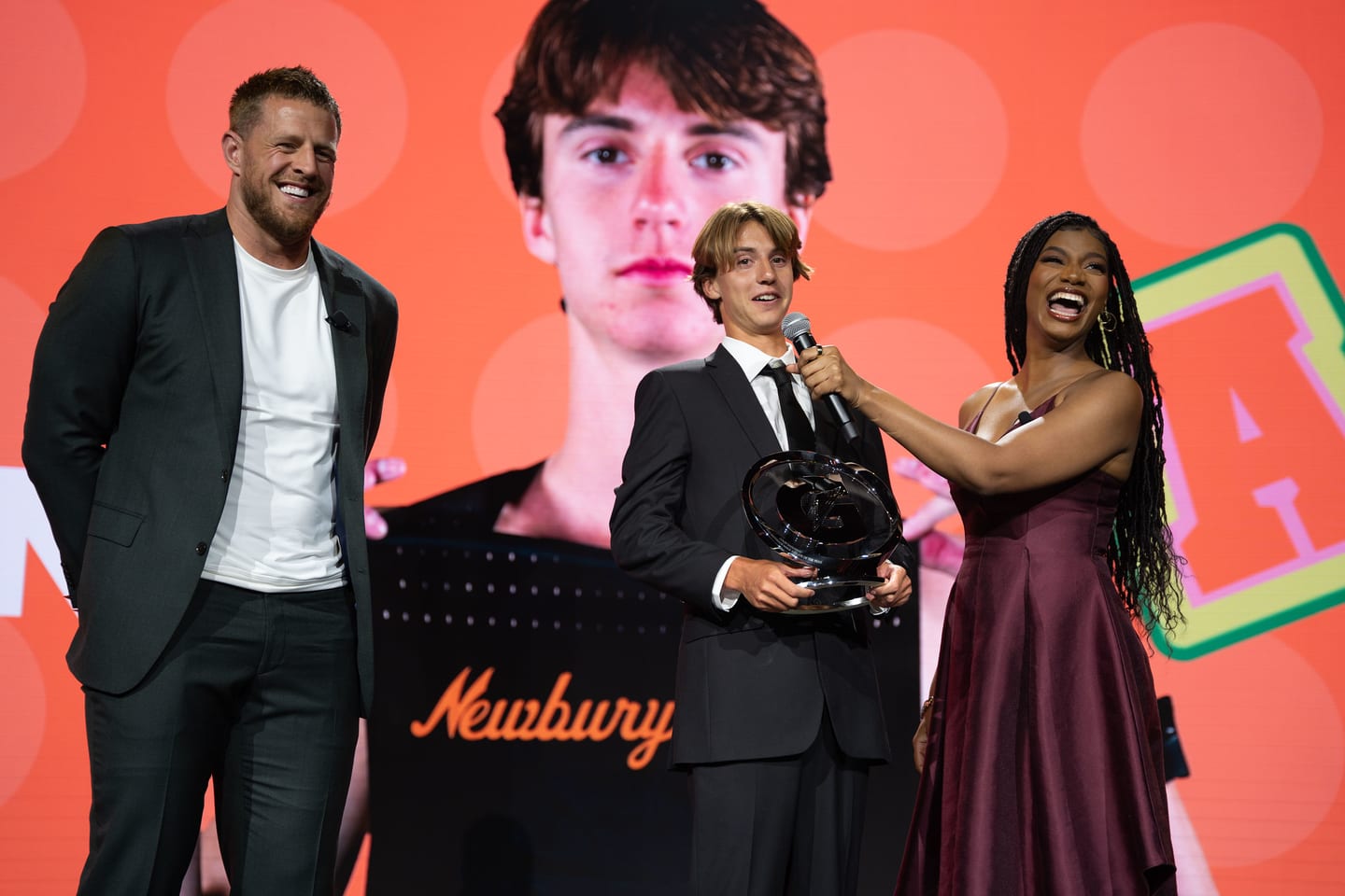 An honoree accepting his trophy on stage between two presenters
