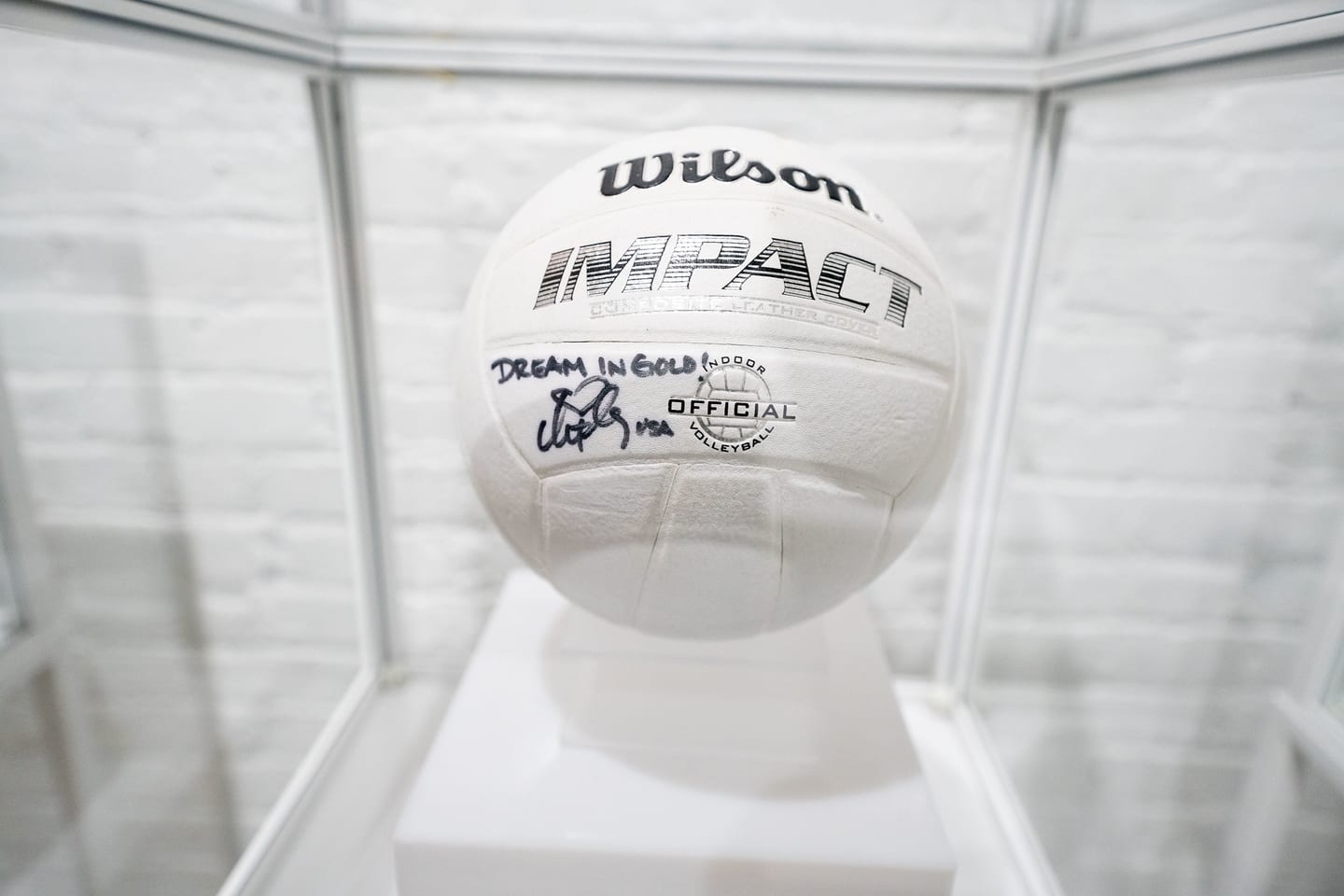 A signed Wilson Impact volleyball displayed in a clear case