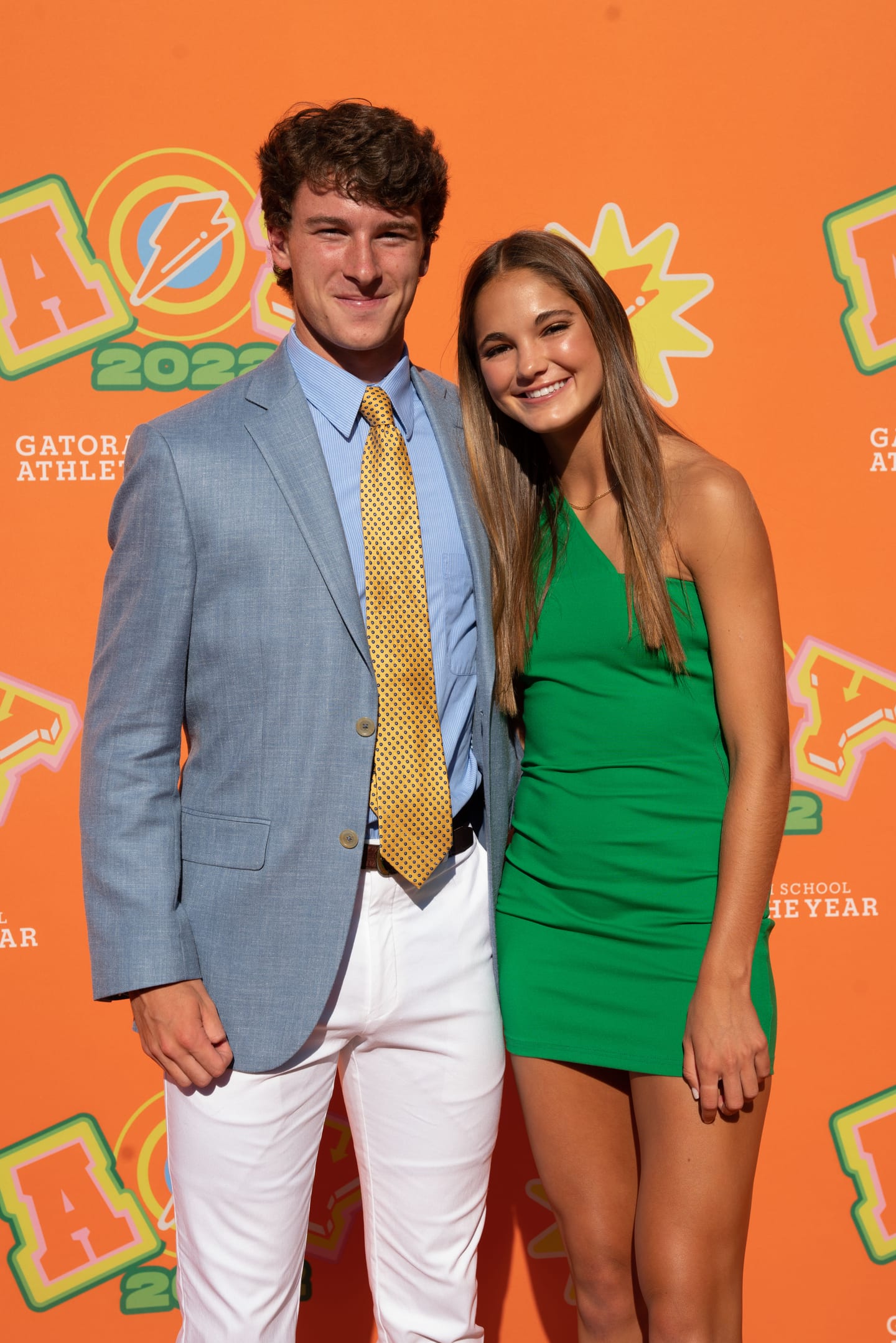 A couple photographed together on the orange Athlete of the Year step-and-repeat