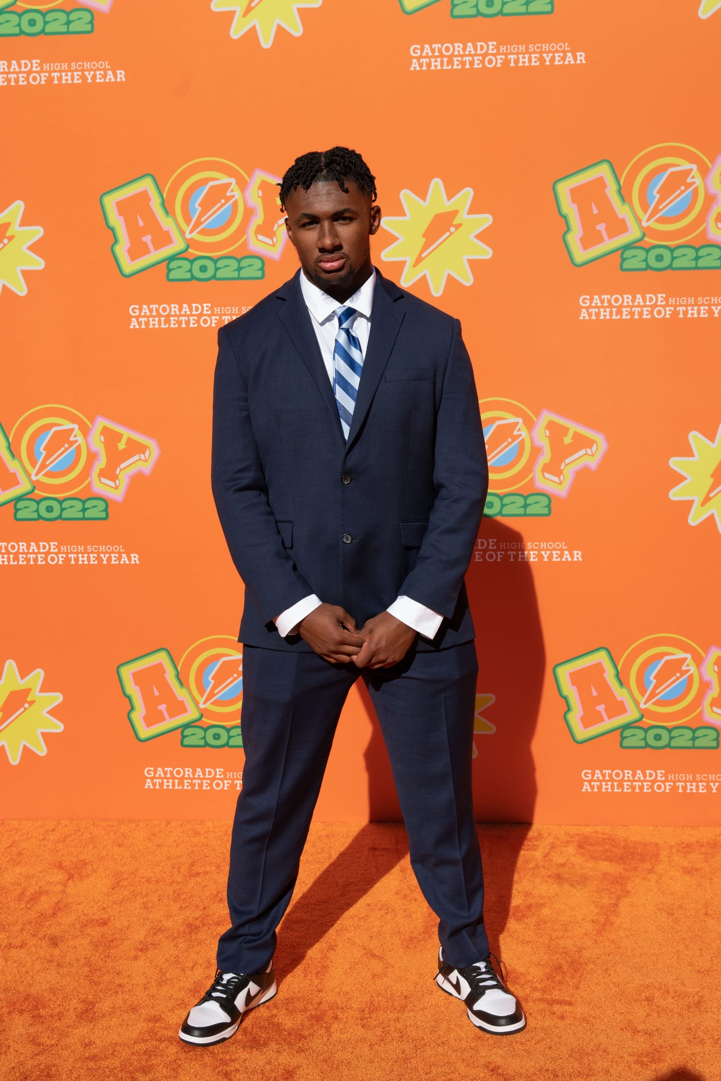 An honoree in a navy suit photographed on the orange AOY 2022 step-and-repeat