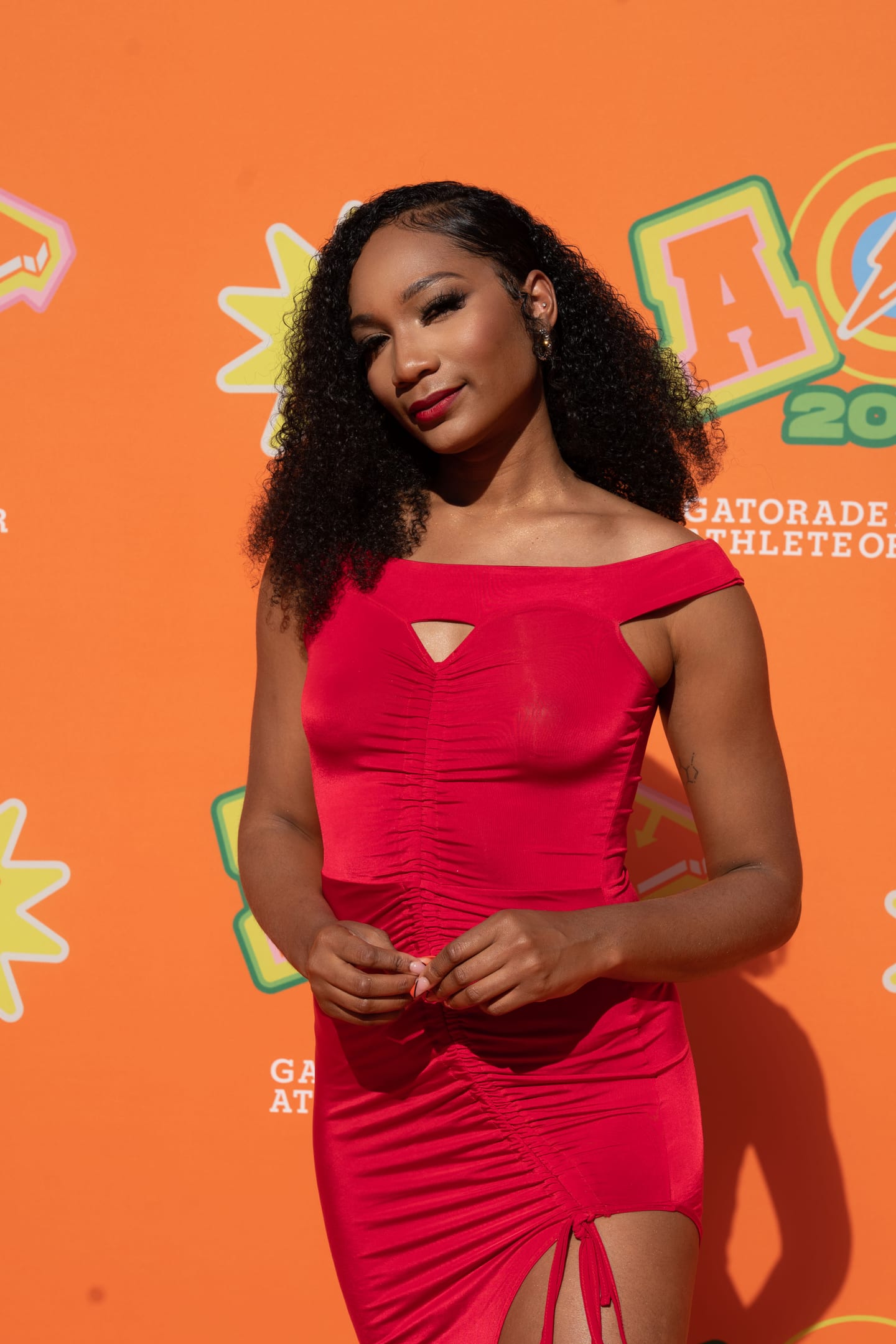 An honoree in a red dress photographed on the orange AOY 2022 step-and-repeat