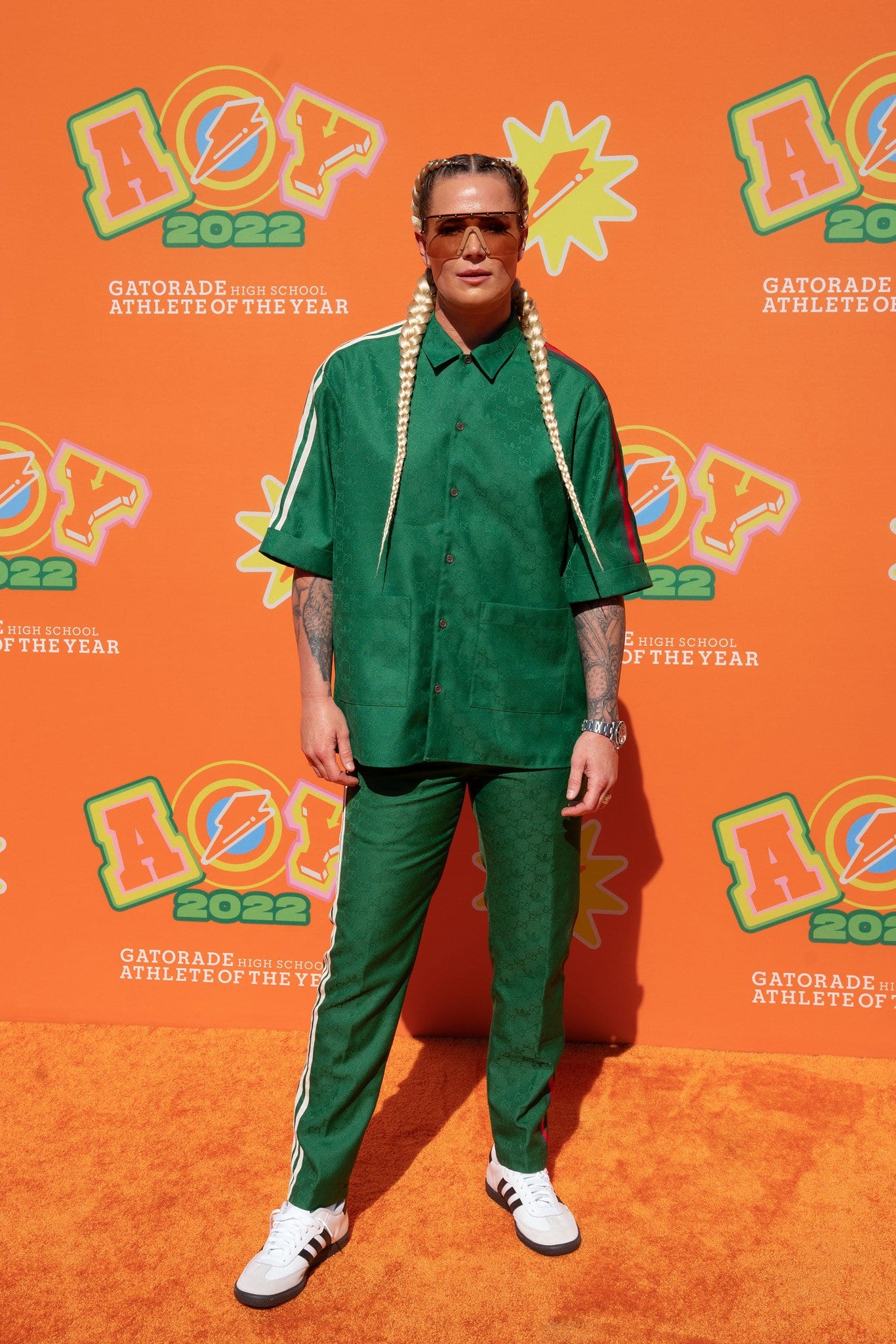 Athlete in a green tracksuit on the orange carpet in front of a Gatorade High School Athlete of the Year 2022 step-and-repeat