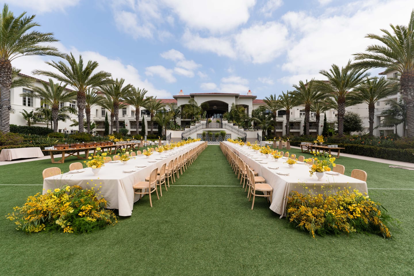Long outdoor dining tables lined with yellow flowers on the lawn at Park Hyatt Aviara for In goop Health 2024