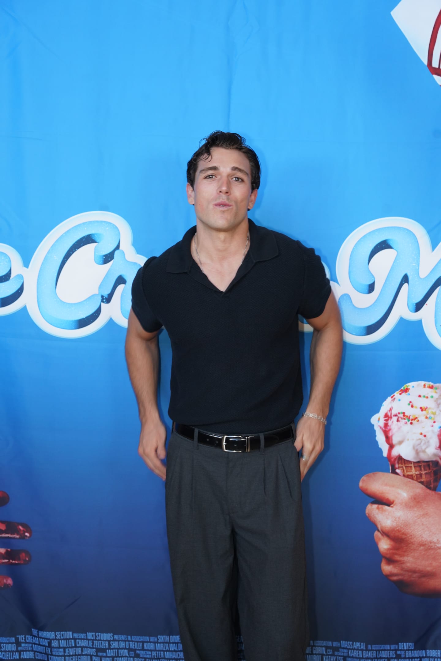 A guest in a black polo shirt posing against the blue Ice Cream Man branded backdrop at the Glendale premiere-week screening