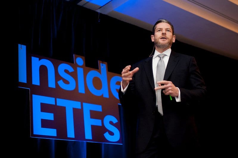 Speaker on stage in front of a large “Inside ETFs” screen at a finance conference