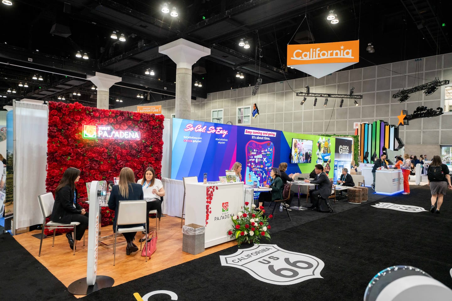 Rows of California destination exhibitor booths with meetings underway on the IPW trade show floor