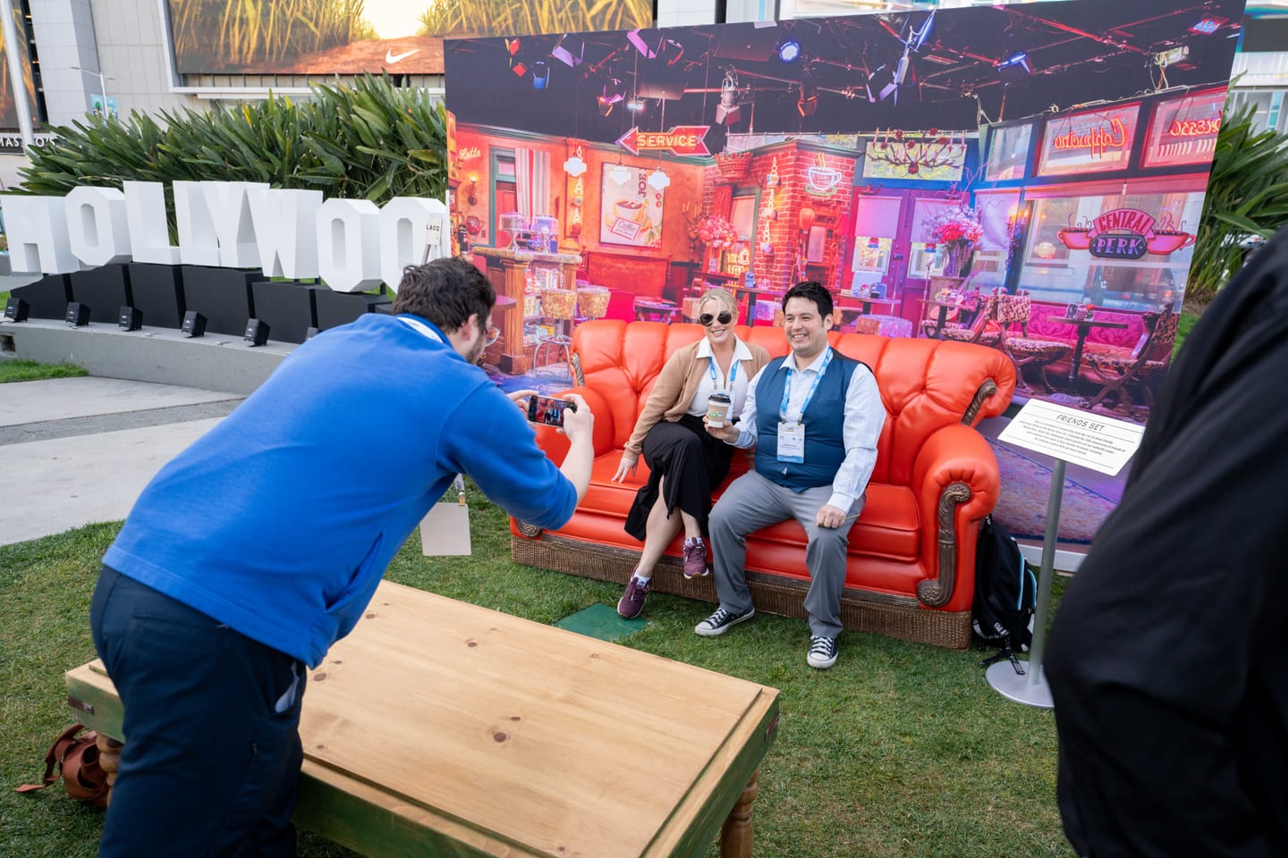A photographer shooting two delegates seated on a replica Central Perk orange couch at an outdoor photo activation at IPW
