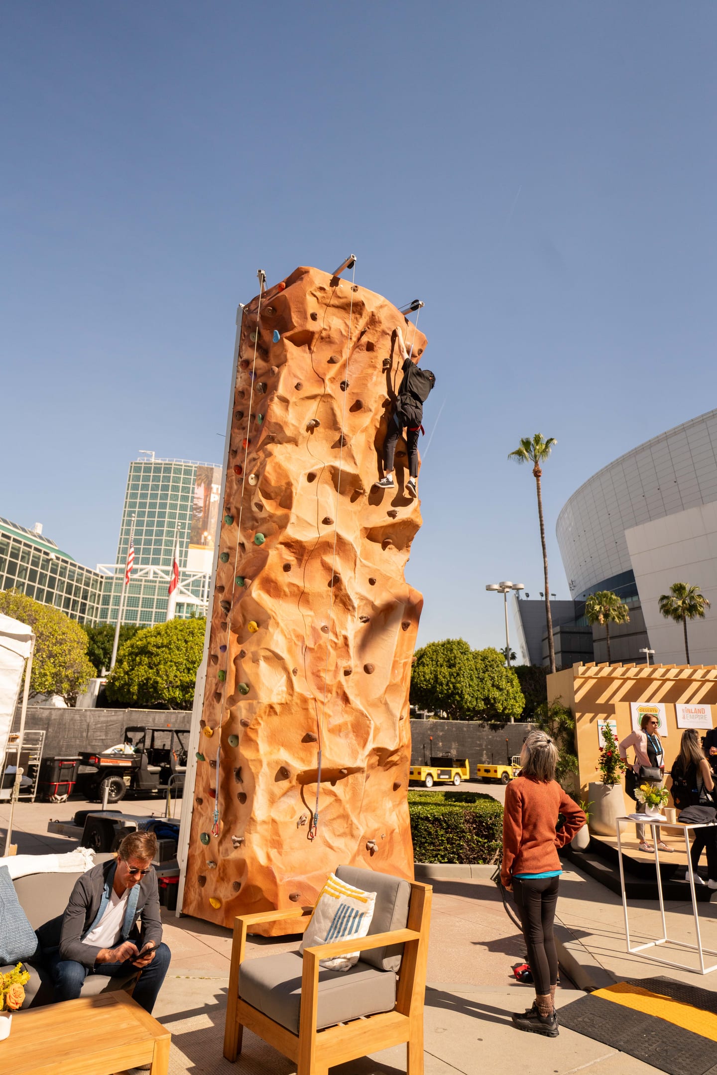 A tall outdoor climbing wall set up on the Los Angeles Convention Center plaza at IPW
