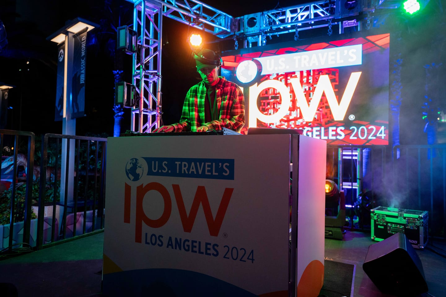 A U.S. Travel IPW Los Angeles 2024 branded booth on a smoky lit stage at the closing party