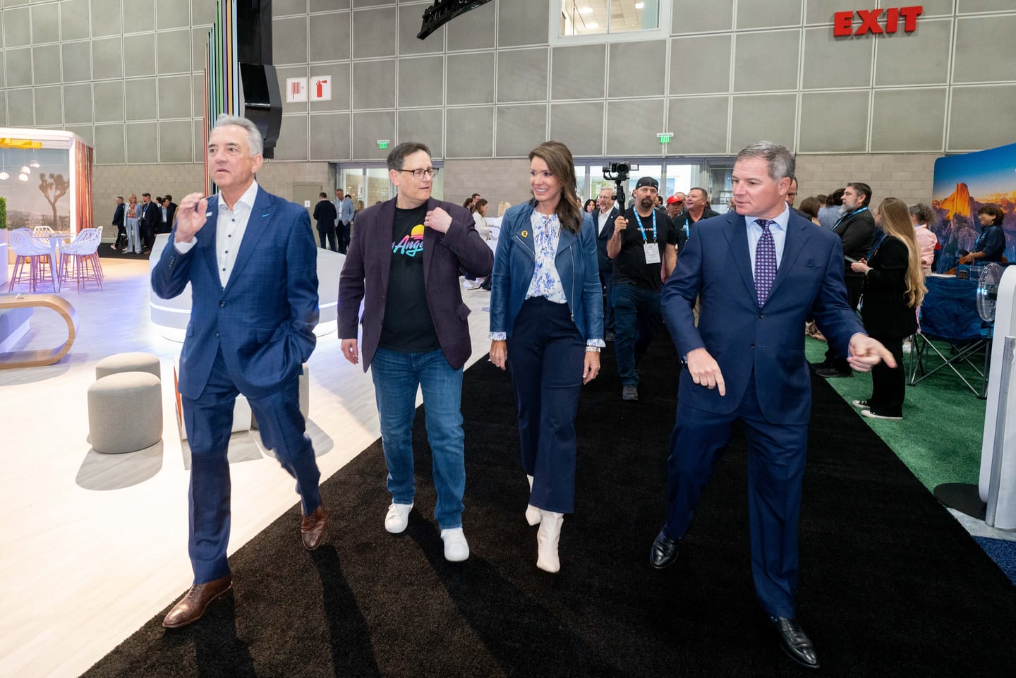 Executives walking and talking down a black-carpeted aisle of the IPW Marketplace floor
