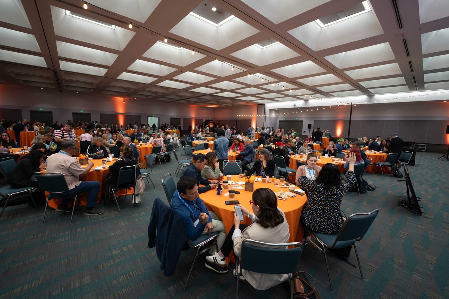 A ballroom of orange-dressed tables at the Visit Orlando sponsored media breakfast during IPW
