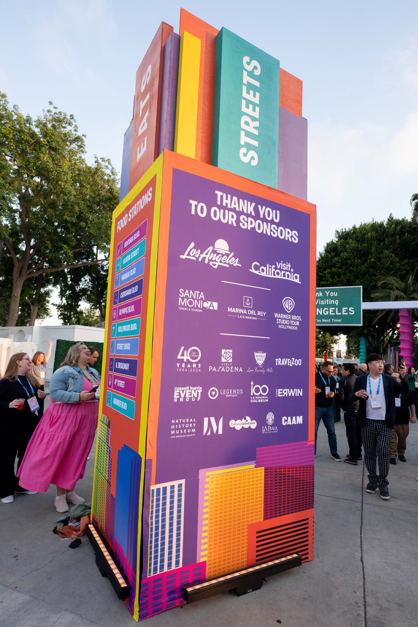 A colorful Thank You To Our Sponsors tower with partner logos at an outdoor IPW event space