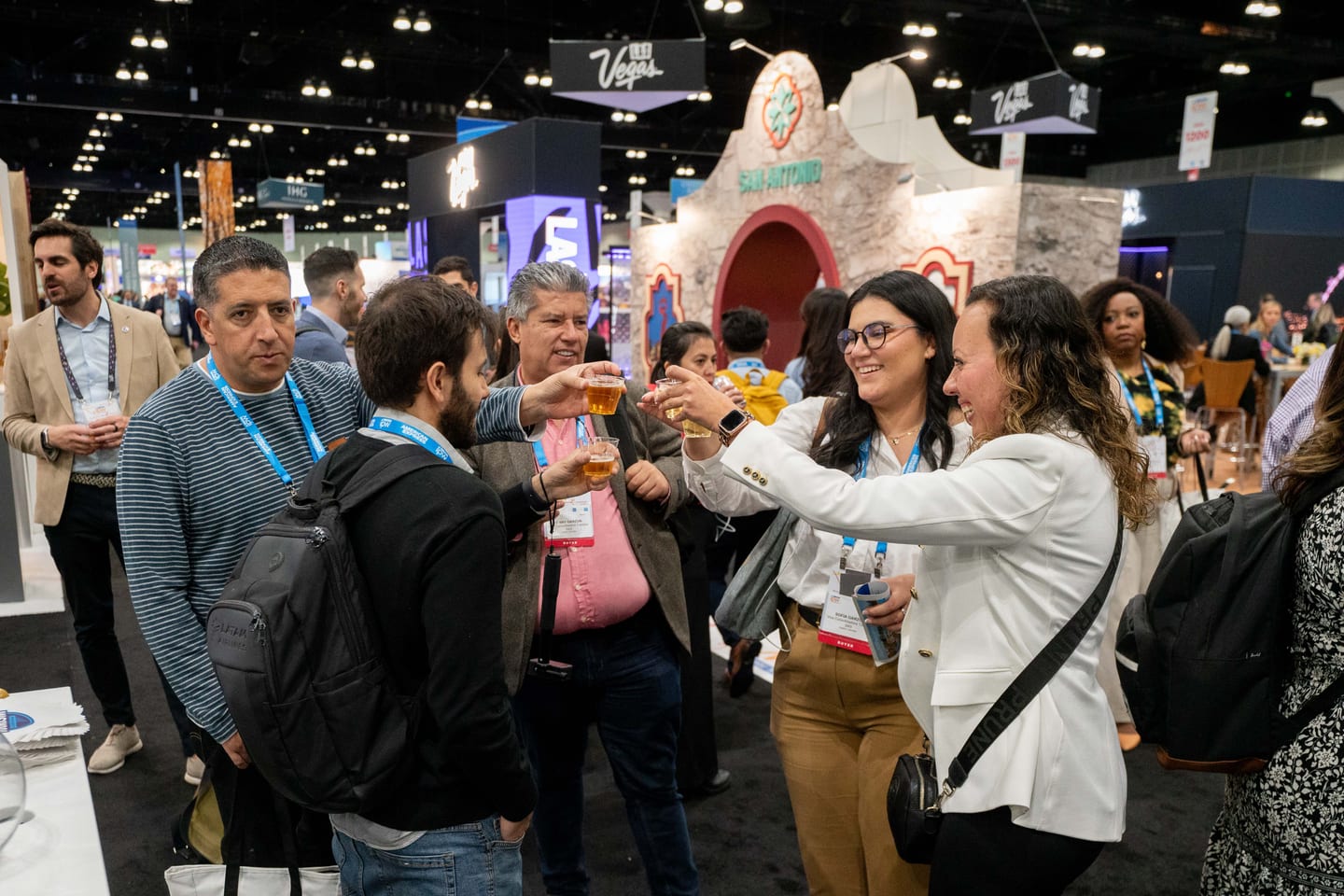 IPW delegates raising plastic cups in a toast on the Marketplace floor beside a Las Vegas booth