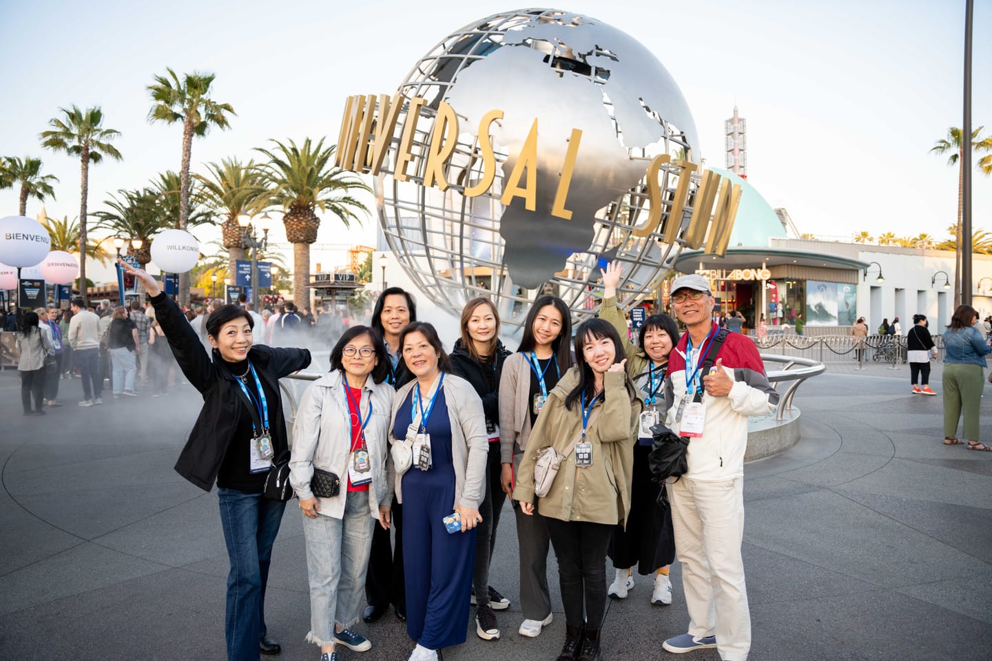 A group of IPW delegates posing and waving at the Universal Studios globe at the closing party