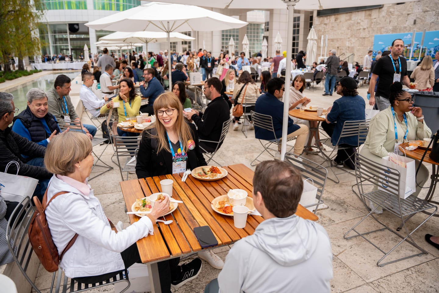 IPW delegates eating brunch at outdoor tables under umbrellas on a daylight terrace