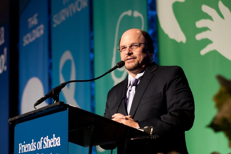 Actor Jason Alexander speaking at a podium at the Friends of Sheba Medical Center gala