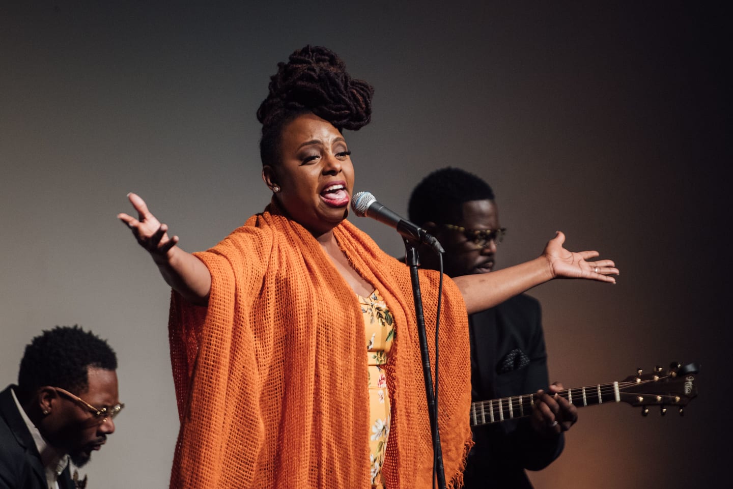 A vocalist in an orange wrap performing with her band at the Global Green pre-Oscar gala